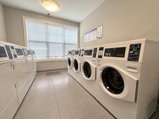 A row of white front load washing machines in a laundromat.