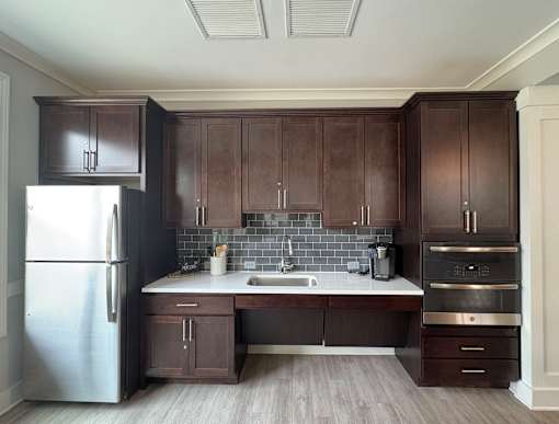 A kitchen with dark brown cabinets and a stainless steel refrigerator.