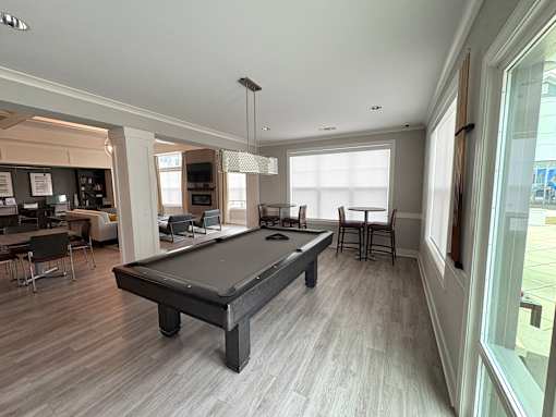 A pool table is in the middle of a room with a lot of windows.