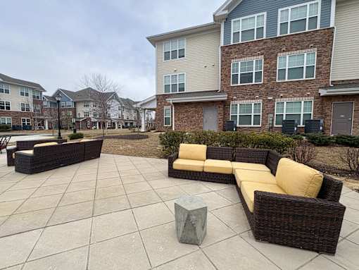 A patio with a couch and a table in front of a building.