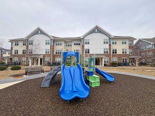 A playground with a blue slide in front of apartment buildings.