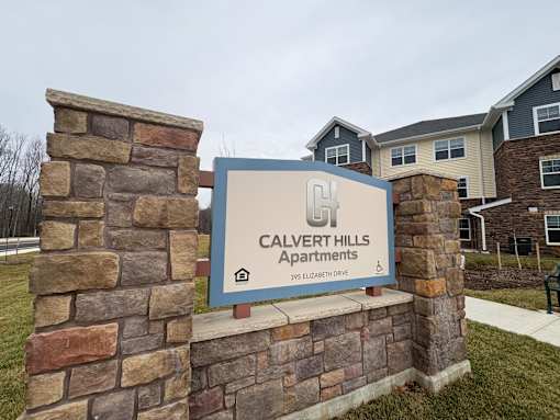 A sign for Calvert Hills Apartments stands in front of a building.