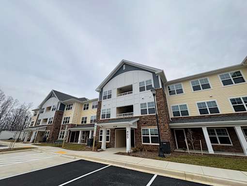 Apartment complex with a parking lot in front.