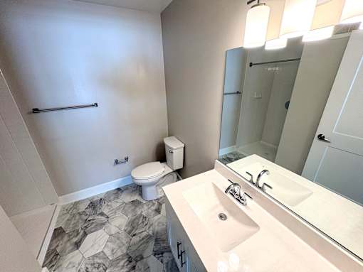 A bathroom with a toilet, sink, and mirror.