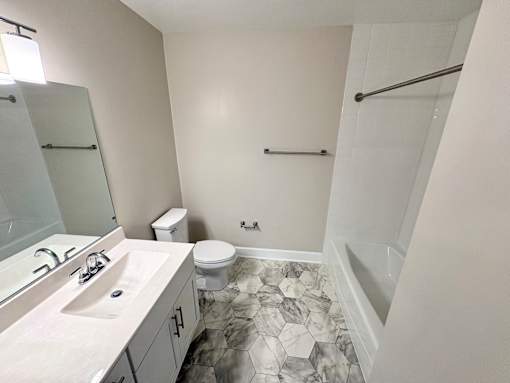 A bathroom with a marble floor and white walls.