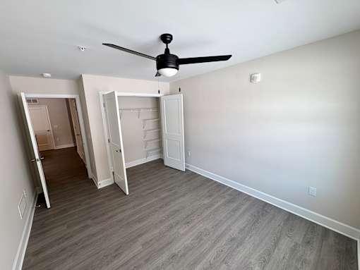A room with a ceiling fan and a doorway leading to another room.