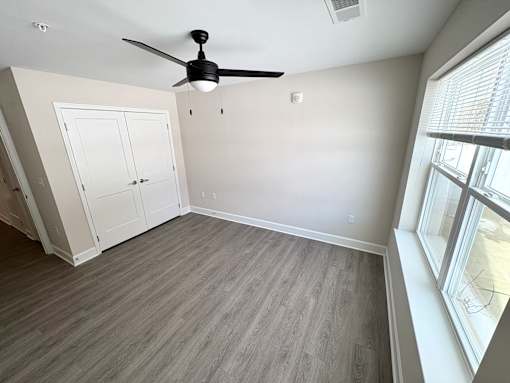A room with a ceiling fan and a window with blinds.