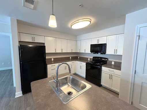 A kitchen with black appliances and white cabinets.