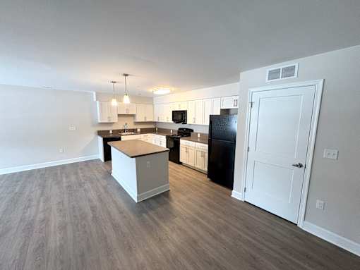 A kitchen with a black fridge and white cabinets.