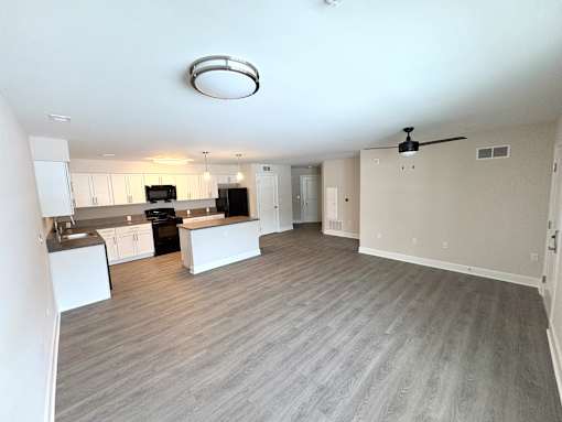 A spacious kitchen and living room with a ceiling fan and light fixture.