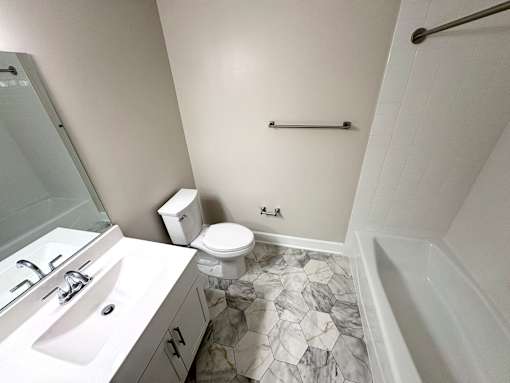 A bathroom with a marble floor and white walls.