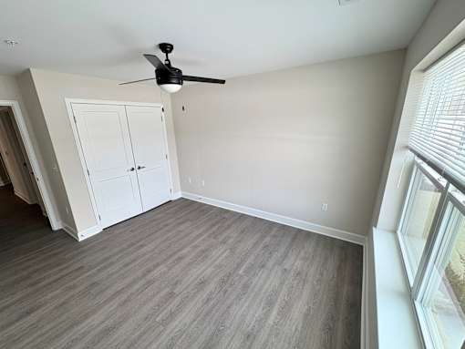 A room with a ceiling fan and a large window.