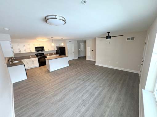 A spacious kitchen with a grey floor and white walls.