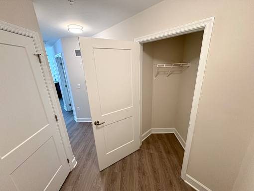 A white closet with a shelf and a door open.