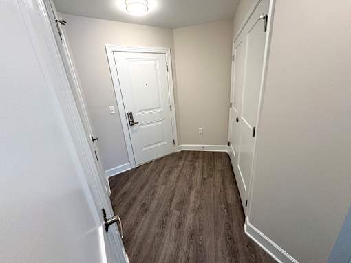 A room with a white door and a wooden floor.