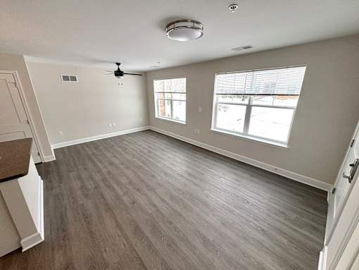 A room with a ceiling fan and two windows.
