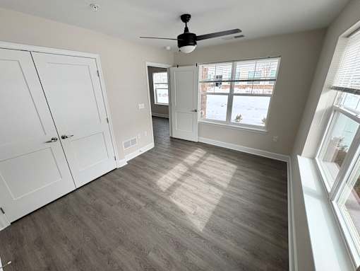 A room with a ceiling fan and a window with blinds.
