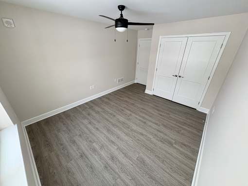 A room with a ceiling fan and a wooden floor.