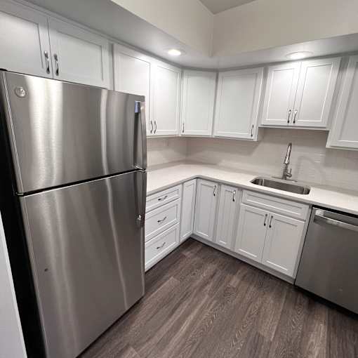 A kitchen with a stainless steel refrigerator and white cabinets.