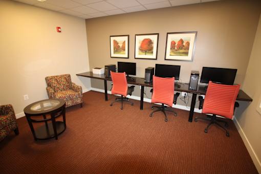 A conference room with a carpeted floor and a long table with chairs.