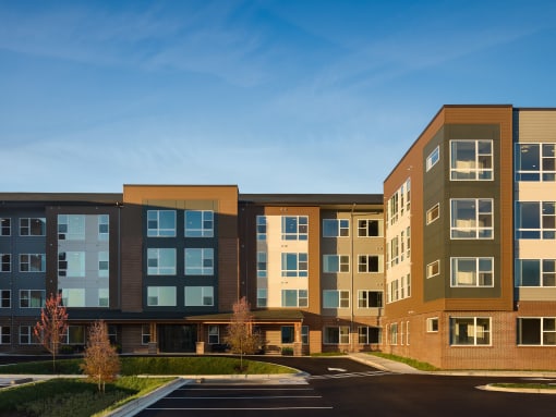 an exterior view of an apartment building with a parking lot
