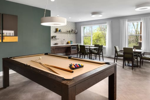 a pool table in a living room with a dining room and a kitchen