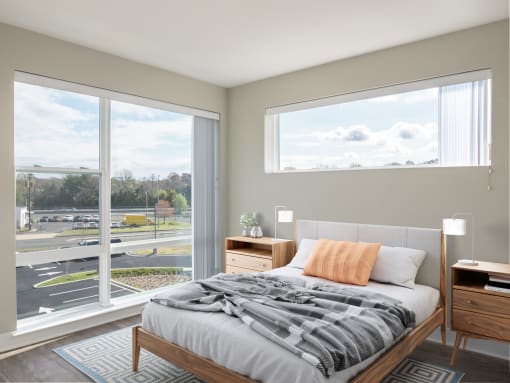 a bedroom with a large window and a bed with a blanket