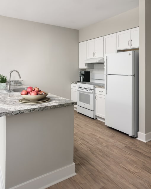 a kitchen with white appliances and a bowl of fruit on the counter