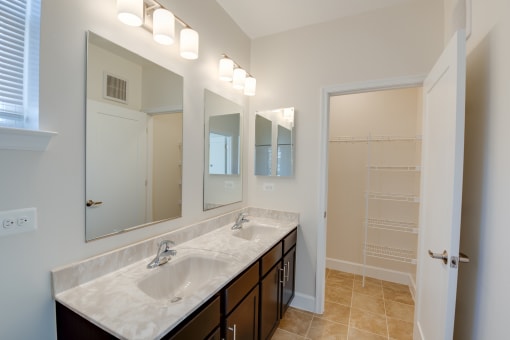 bathroom with marble sink and countertop with large lighted mirror