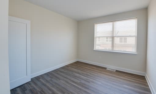 a bedroom with hardwood floors and a large window