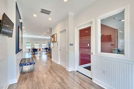 a long hallway with white walls and wood floors and a door to a dining room