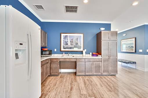 a kitchen with wooden floors and blue walls and a refrigerator