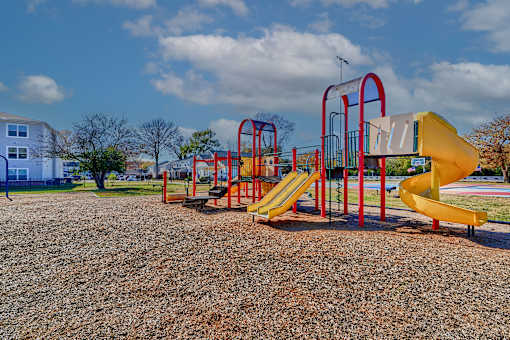 a playground at a park with yellow and red playsets