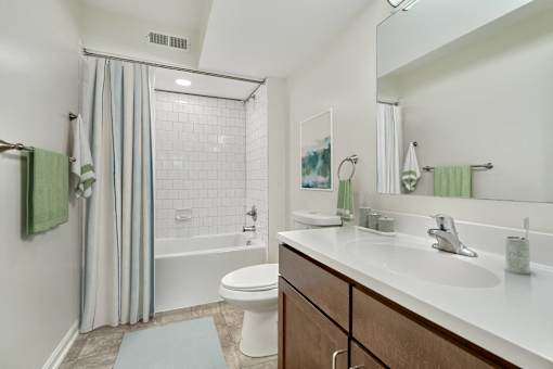 A white toilet sits in a bathroom with a white sink and a white bathtub.