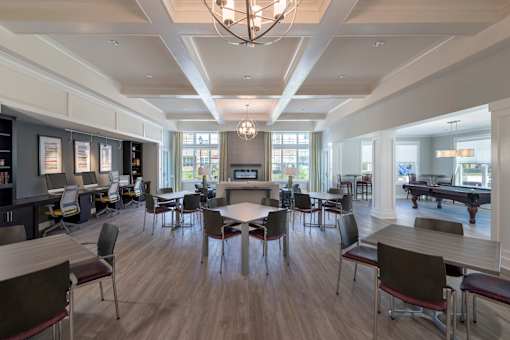 A large room with tables and chairs and a pool table.