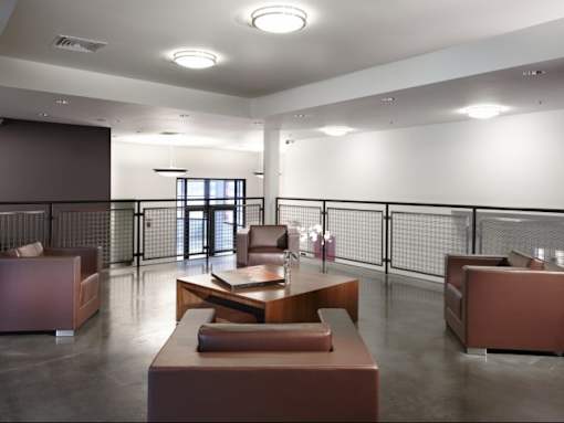 A modern waiting room with brown furniture and a glass door.