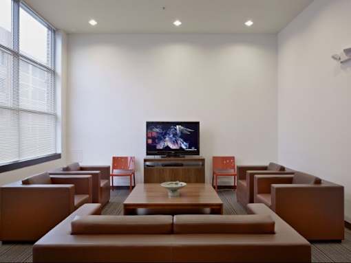 A room with brown leather couches and a television playing a movie.