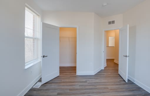 a bedroom with hardwood floors and white walls