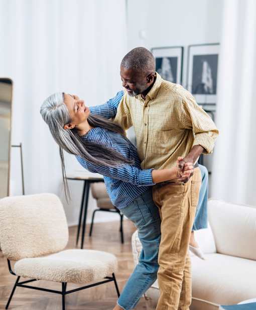 A man lifts a woman in a living room setting.