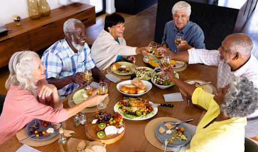 A group of people toasting with wine glasses at a dinner table.