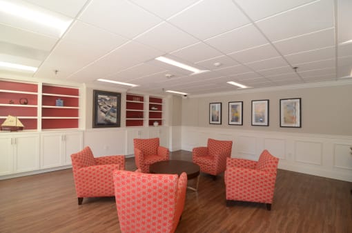 a waiting room with red chairs and paintings on the wall