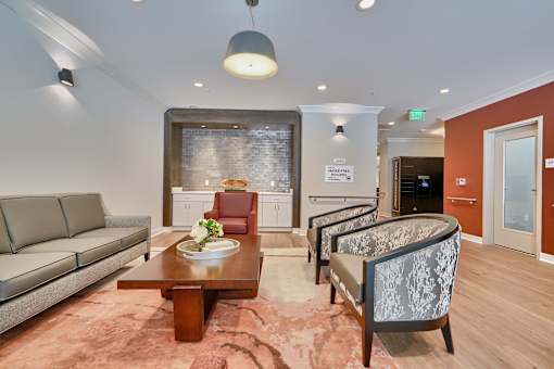 A living room with a grey sofa, a wooden coffee table, and a patterned armchair.