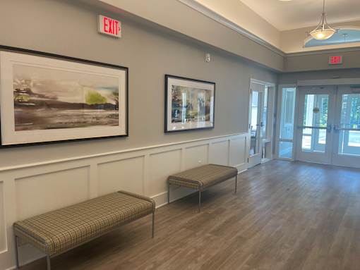 A hallway with two benches and two framed pictures on the wall.