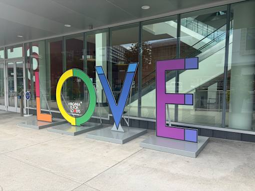 A colorful LOVE sculpture is in front of a building.