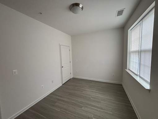 A room with a door and a window with blinds.