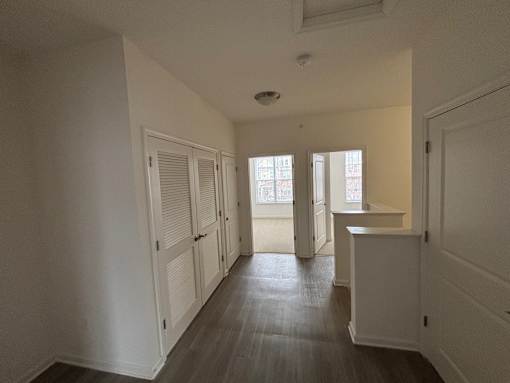 A long hallway with white walls and wood floors.