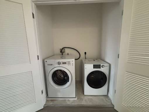 Two white front load washing machines in a small laundry room.