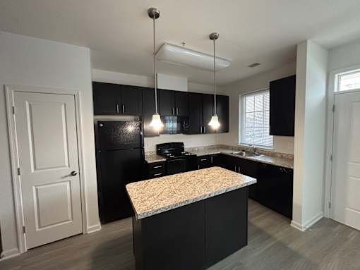 A kitchen with black cabinets and a granite countertop.