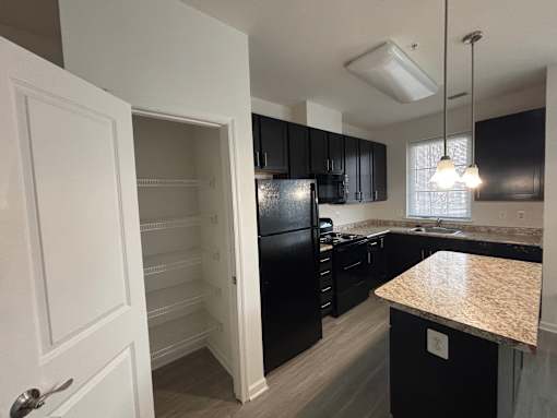 A kitchen with black cabinets and a granite countertop.