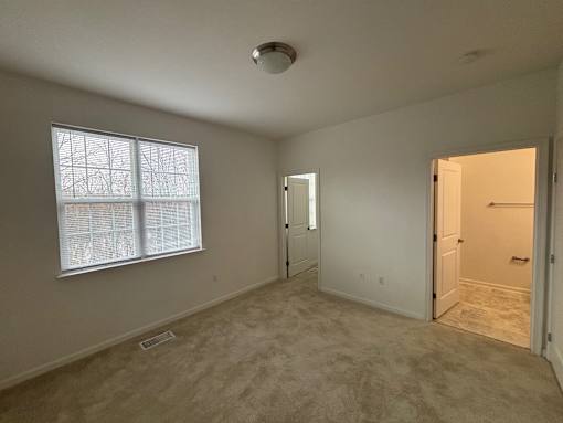 A room with a window, two doors, and a carpeted floor.